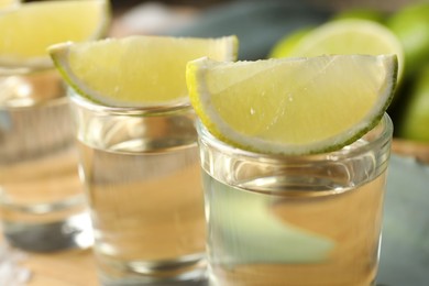 Photo of Tequila shots with lime slices on table, closeup