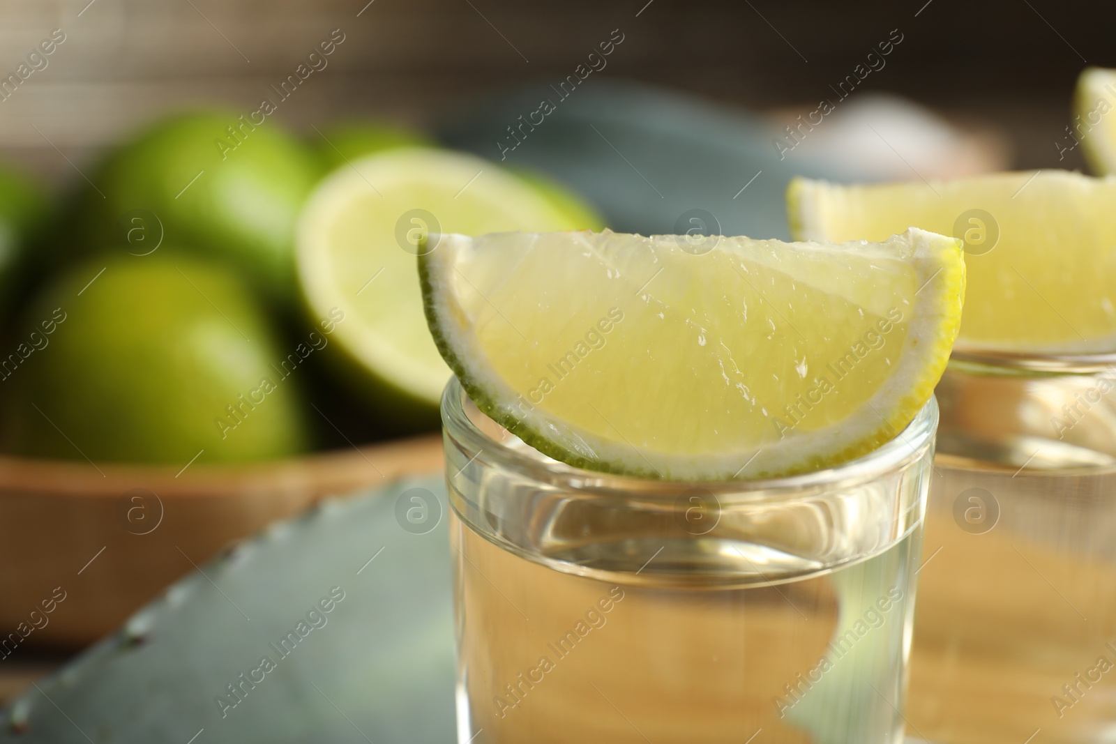 Photo of Tequila shot with lime slice on table, closeup