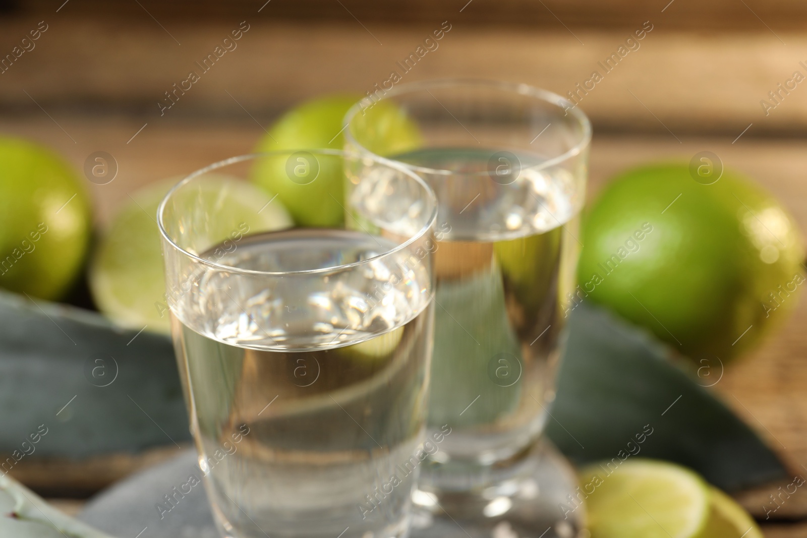 Photo of Tequila shots with limes on table, closeup