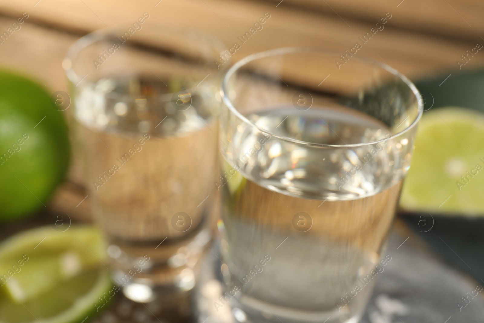 Photo of Tequila shots with limes on table, closeup