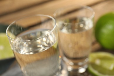 Photo of Tequila shots with limes on table, closeup