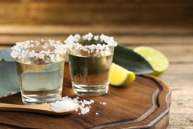 Photo of Tequila shots with salt on wooden table, closeup