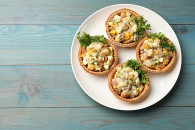 Photo of Tartlets with delicious filling on blue wooden table, top view. Space for text