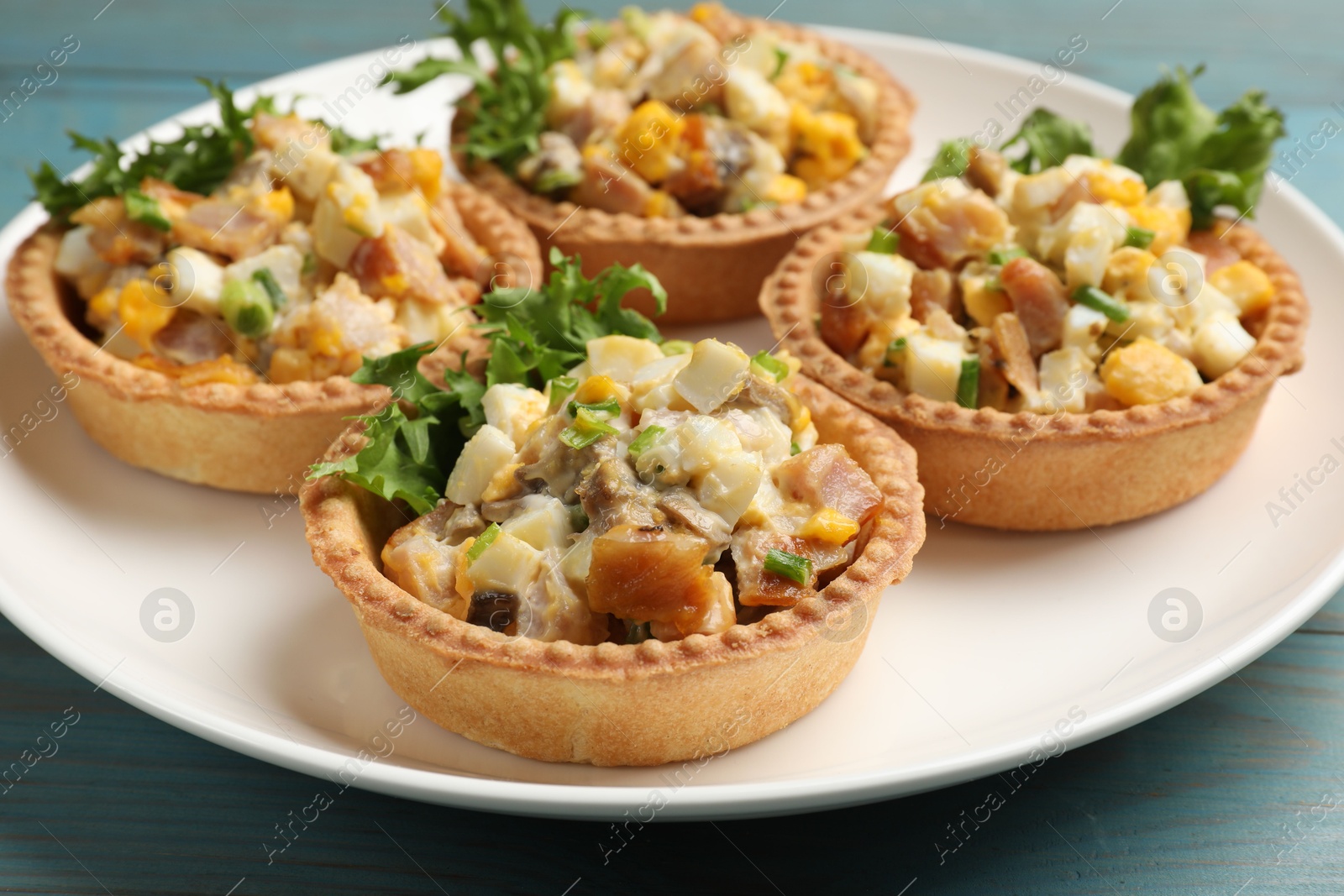 Photo of Tartlets with delicious filling on blue wooden table, closeup