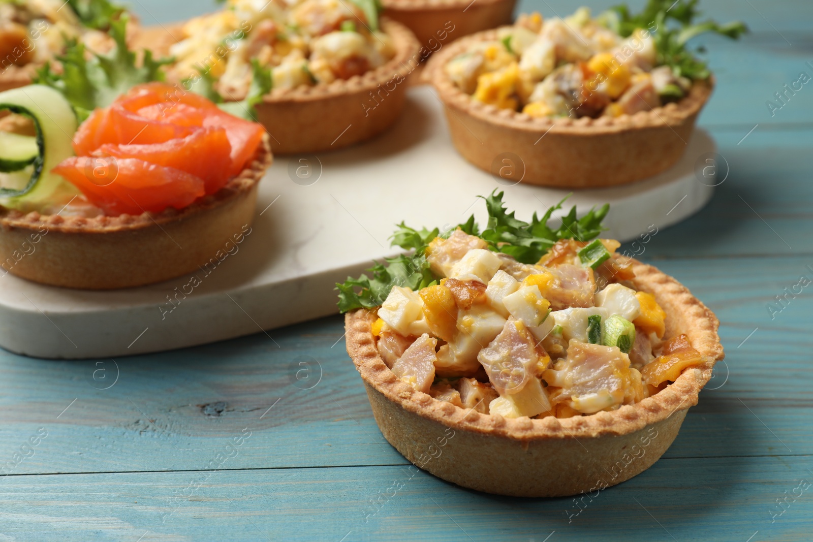 Photo of Tartlets with delicious fillings on blue wooden table, closeup