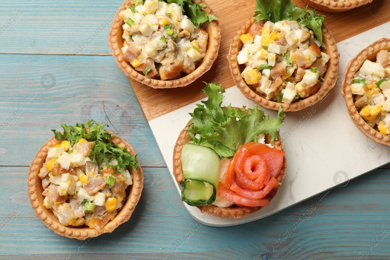 Photo of Tartlets with delicious fillings on blue wooden table, top view