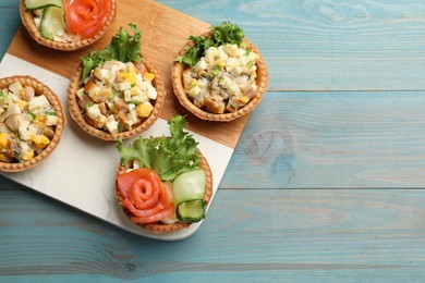 Photo of Tartlets with delicious fillings on blue wooden table, top view. Space for text