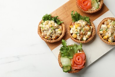 Photo of Tartlets with delicious fillings on white table, top view. Space for text