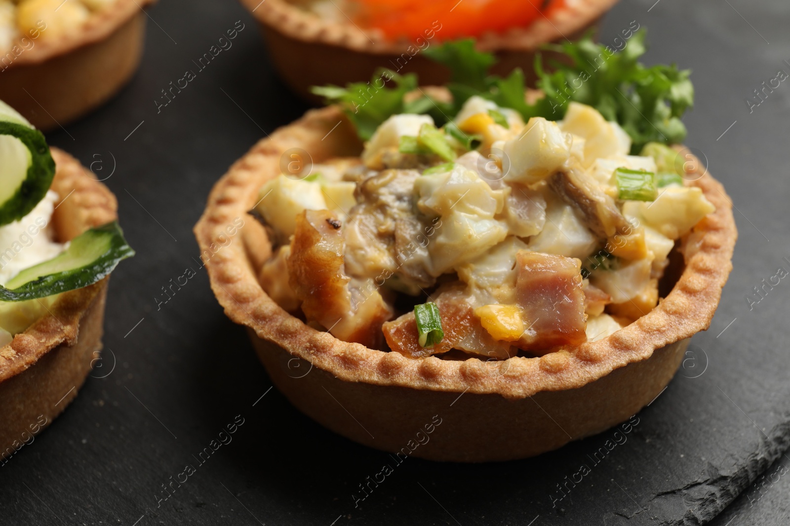 Photo of Tartlets with delicious filling on black table, closeup