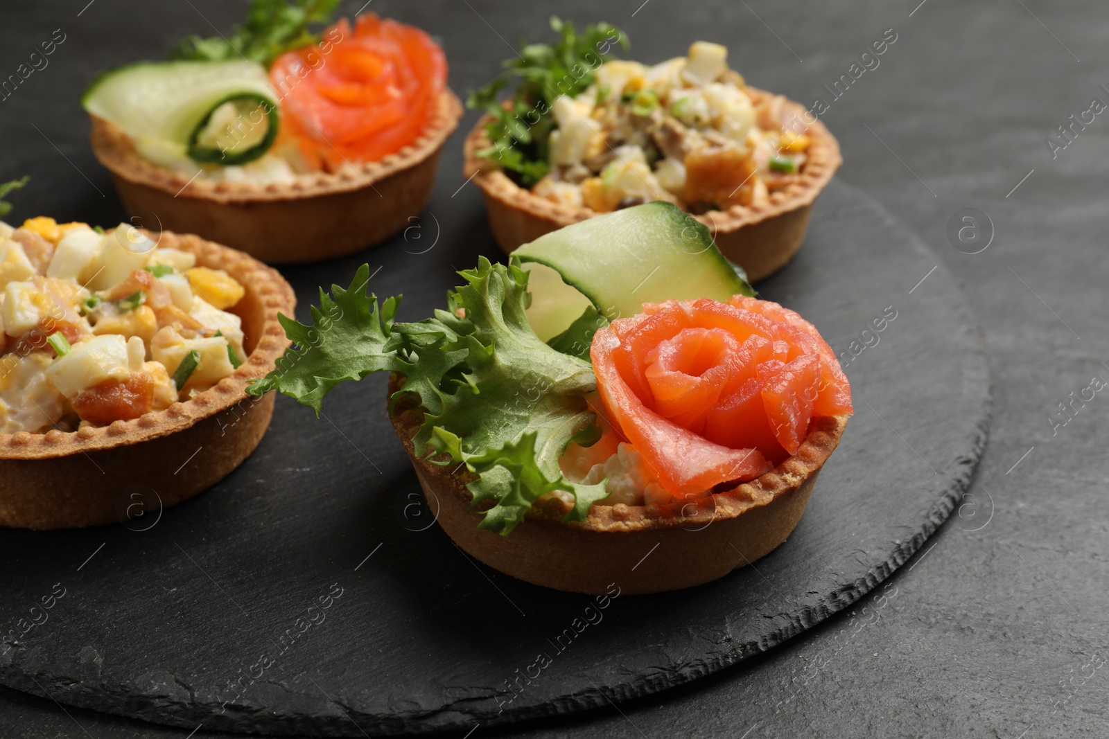 Photo of Tartlets with delicious fillings on black table, closeup