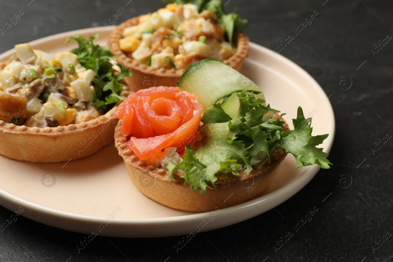 Photo of Tartlets with delicious fillings on black table, closeup