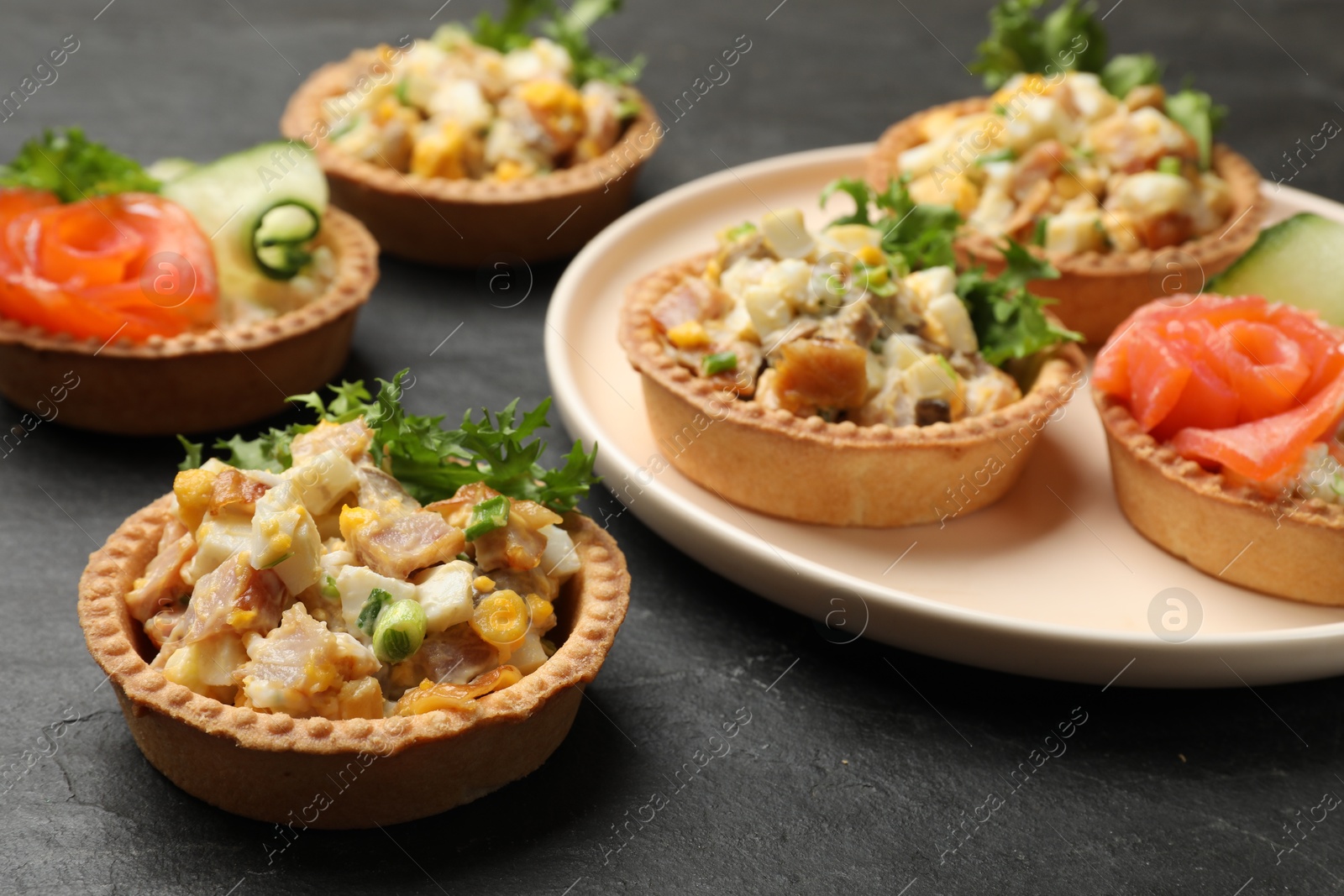 Photo of Tartlets with delicious fillings on black table, closeup