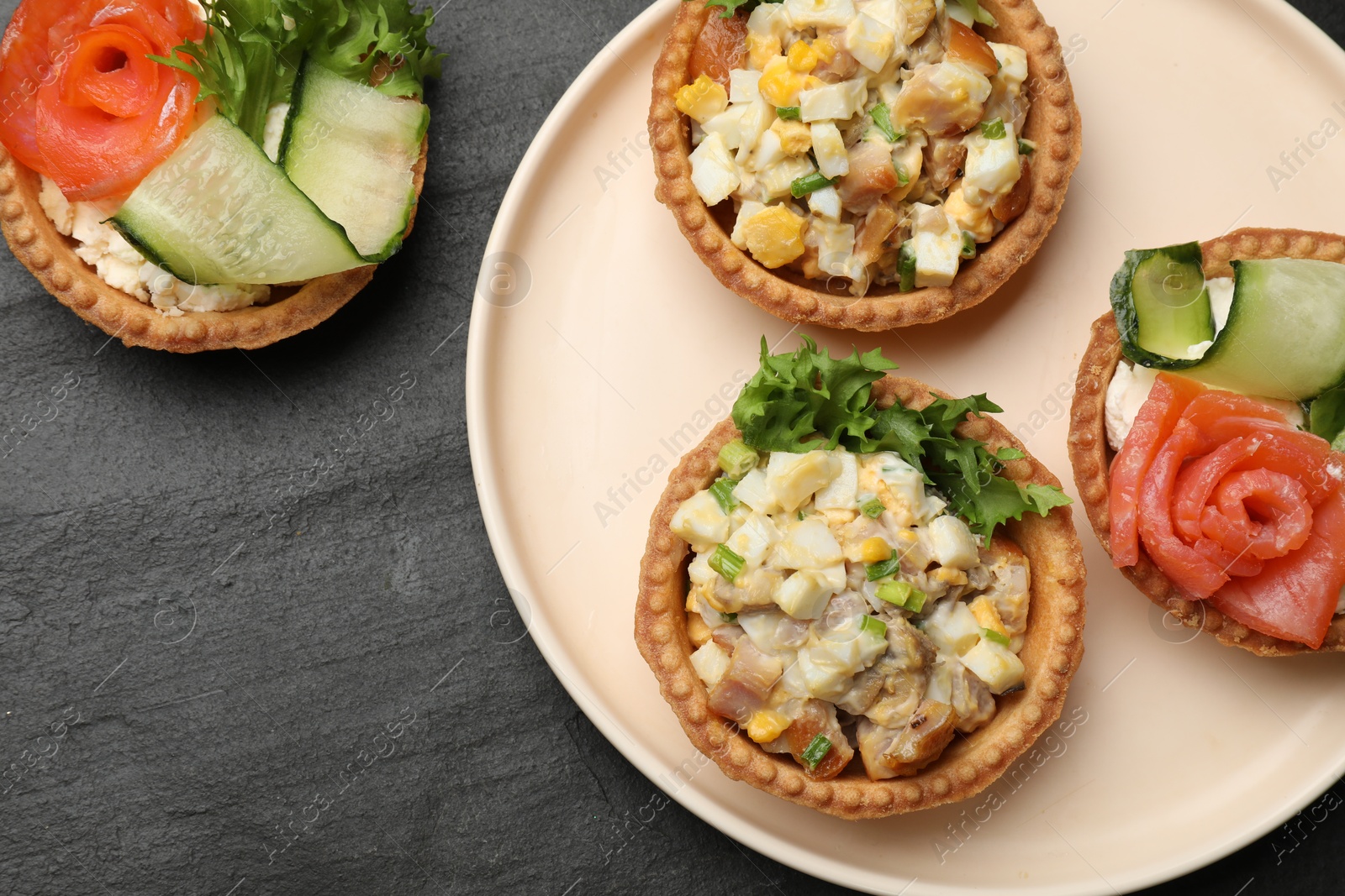 Photo of Tartlets with delicious fillings on black table, top view