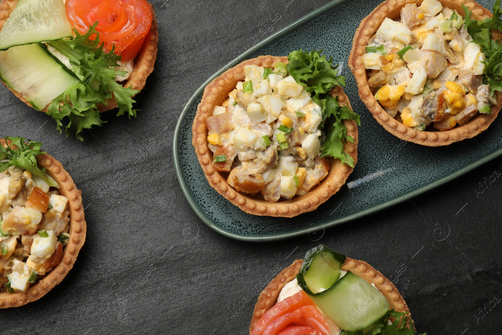 Photo of Tartlets with delicious fillings on black table, top view