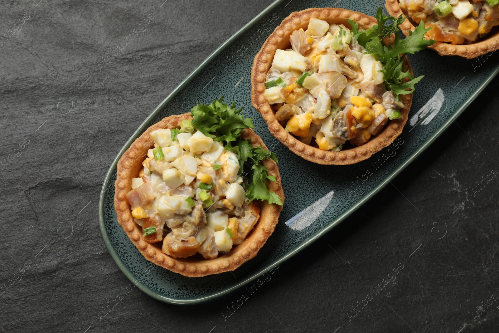 Photo of Tartlets with delicious filling on black table, top view