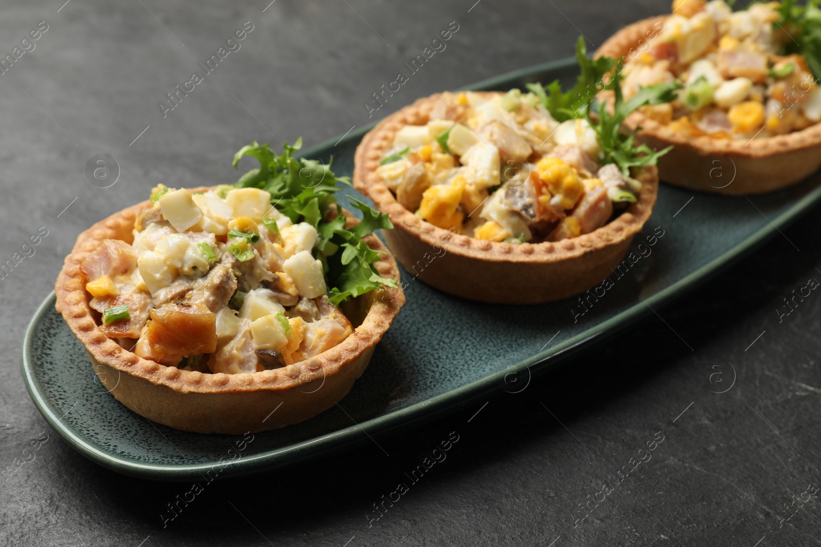 Photo of Tartlets with delicious filling on black table, closeup