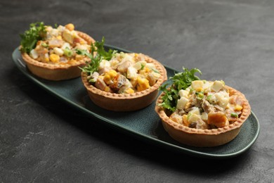 Photo of Tartlets with delicious filling on black table, closeup