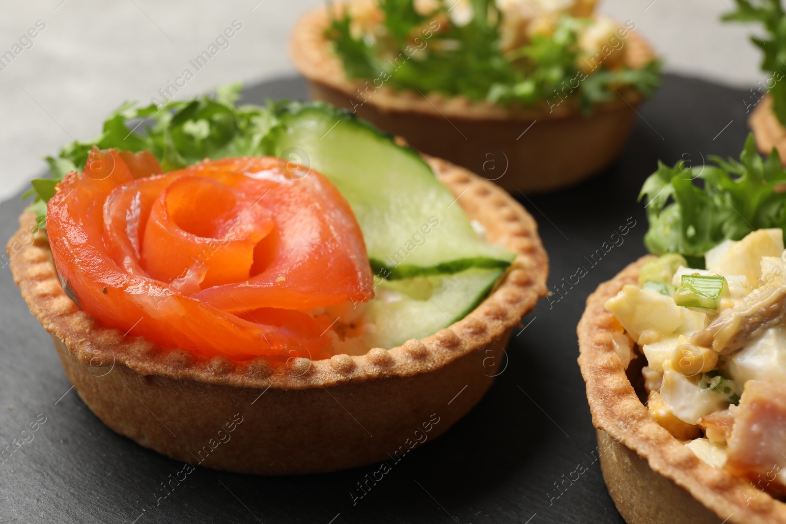 Photo of Tartlets with delicious fillings on grey table, closeup