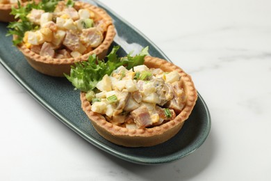 Photo of Tartlets with delicious filling on white marble table, closeup