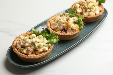 Tartlets with delicious filling on white marble table, closeup