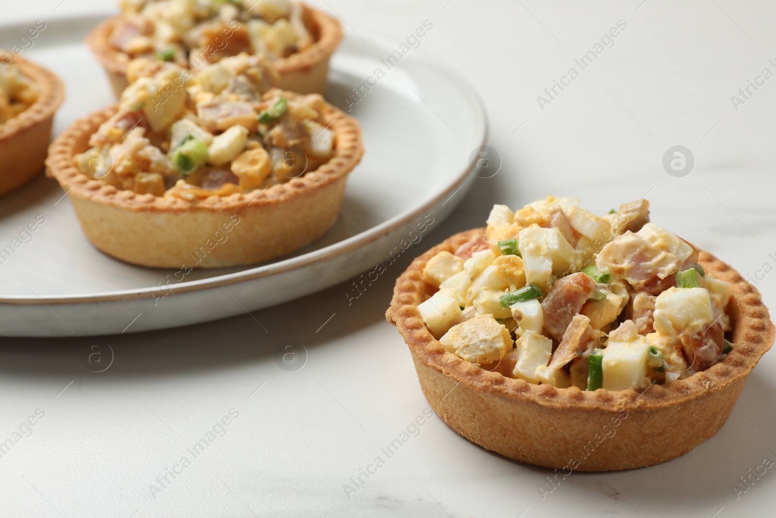 Photo of Tartlets with delicious filling on white marble table, closeup