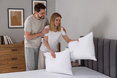 Photo of Couple putting pillows on bed at home. Domestic chores