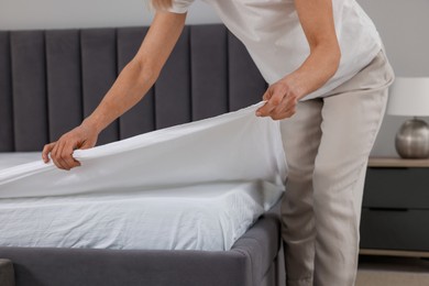 Photo of Woman changing bed linens at home, closeup