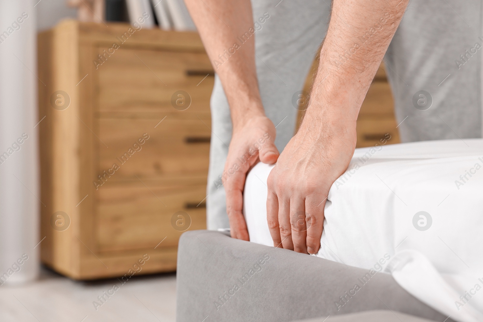 Photo of Man changing bed linens at home, closeup. Space for text