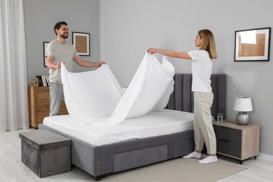 Photo of Couple changing bed linens in room. Domestic chores