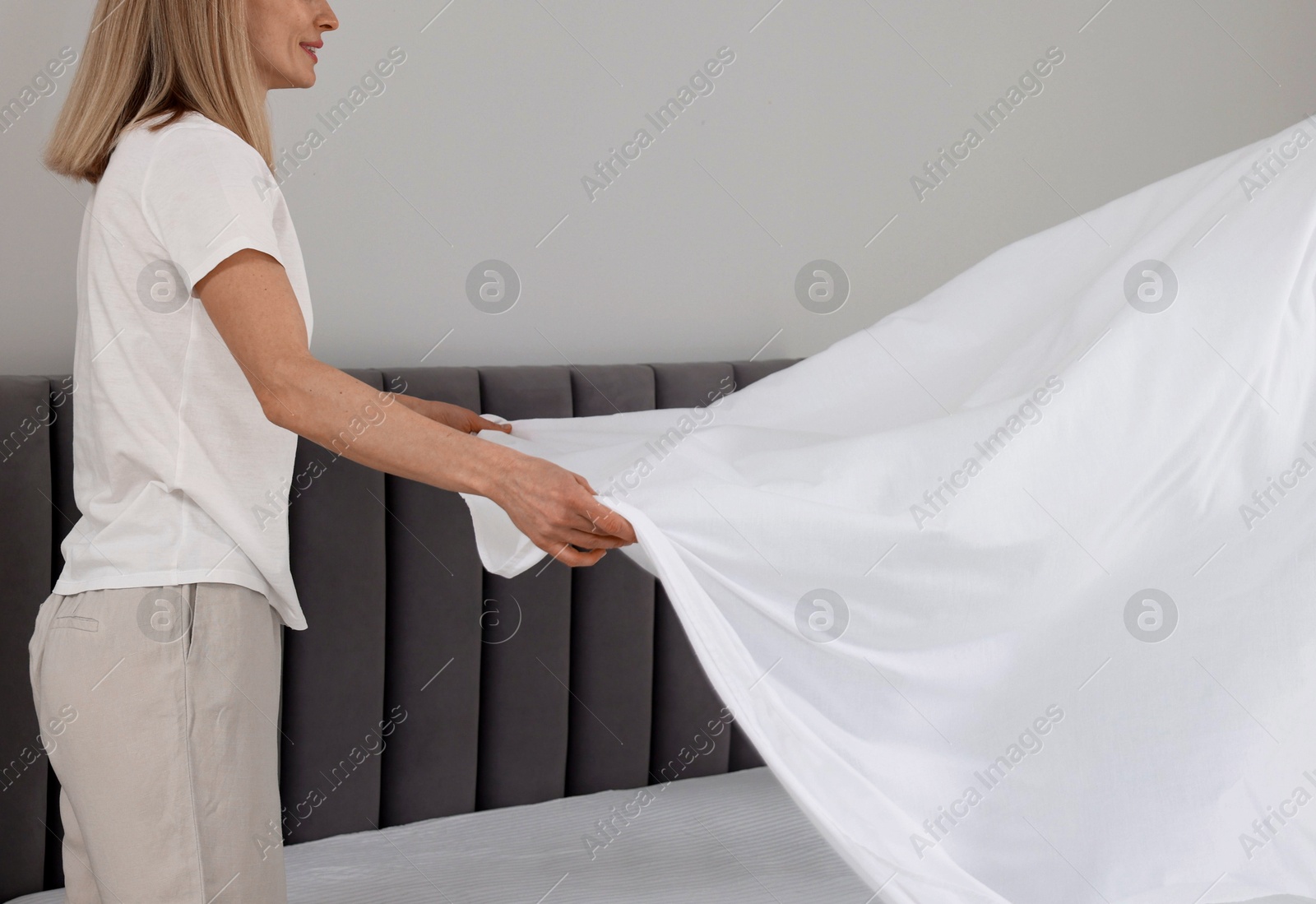 Photo of Woman changing bed linens at home. Space for text