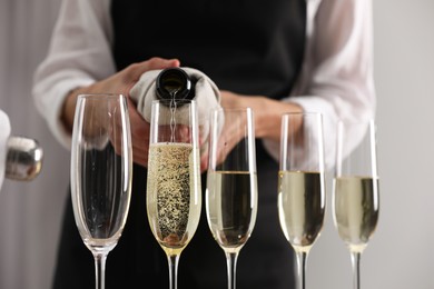 Photo of Waiter filling glasses with champagne indoors, closeup