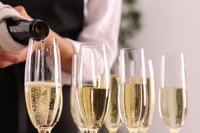 Photo of Waiter filling glasses with champagne indoors, closeup