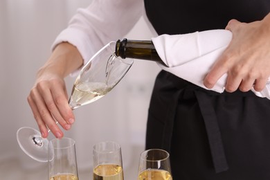 Photo of Waiter pouring champagne into glass indoors, closeup