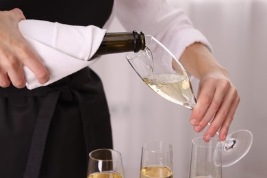 Photo of Waiter pouring champagne into glass indoors, closeup