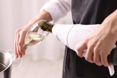 Photo of Waiter pouring champagne into glass indoors, closeup