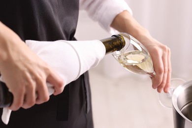 Photo of Waiter pouring champagne into glass indoors, closeup