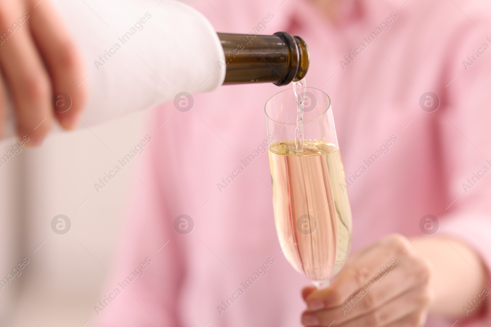 Photo of Waiter pouring champagne into woman's glass, closeup