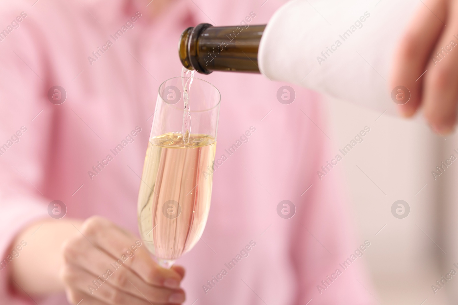 Photo of Waiter pouring champagne into woman's glass, closeup