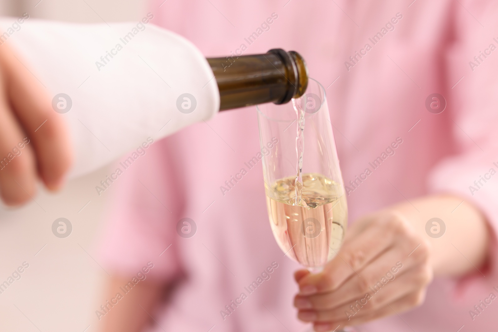 Photo of Waiter pouring champagne into woman's glass, closeup