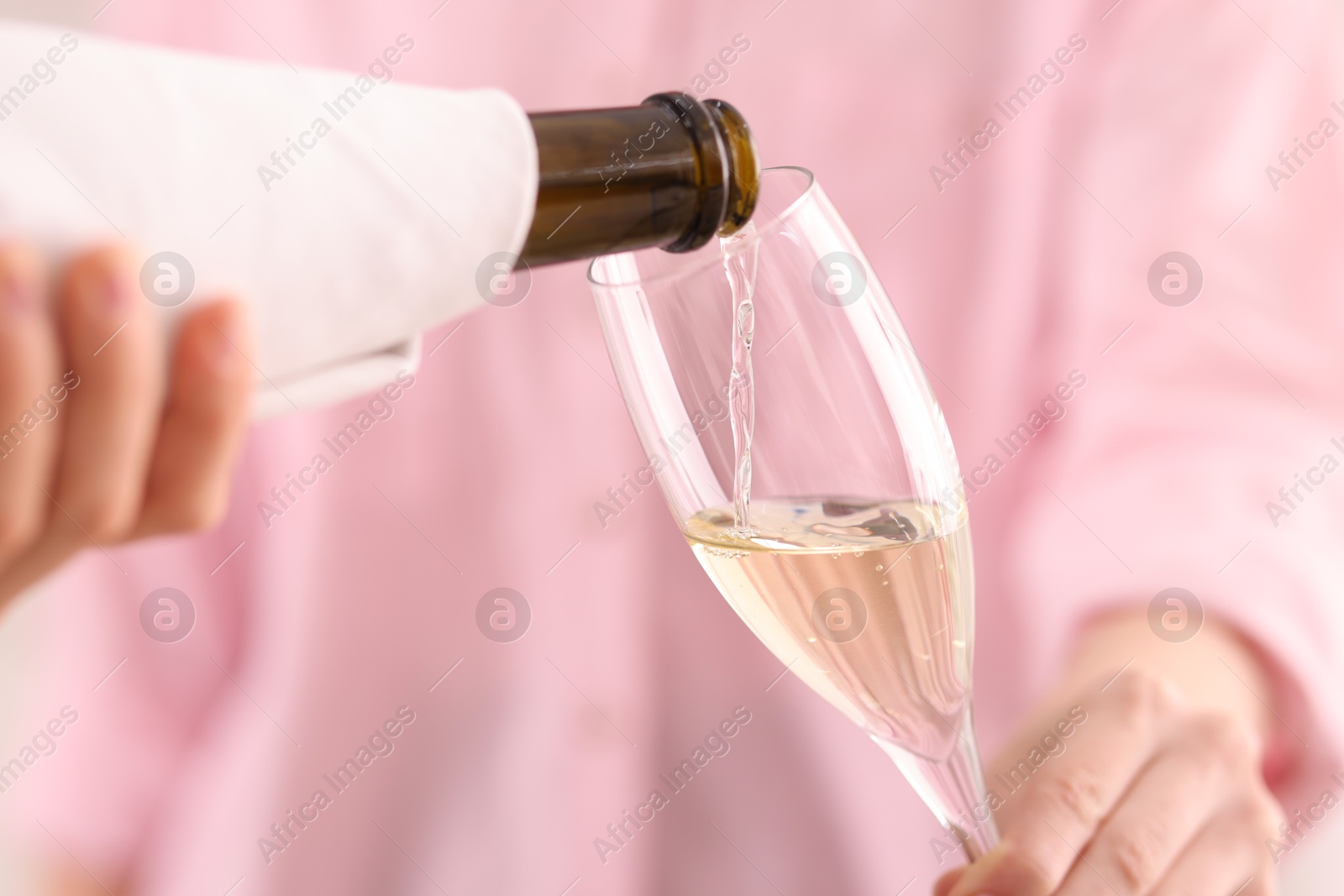 Photo of Waiter pouring champagne into woman's glass, closeup