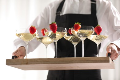 Photo of Waiter holding tray with glasses of champagne indoors, closeup