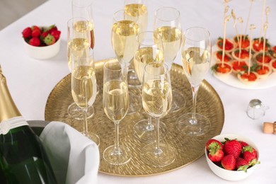 Photo of Champagne, strawberries and canapes with red caviar on white table