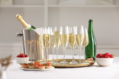 Photo of Champagne, strawberries and canapes with red caviar on white table