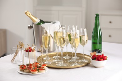 Photo of Champagne, strawberries and canapes with red caviar on white table