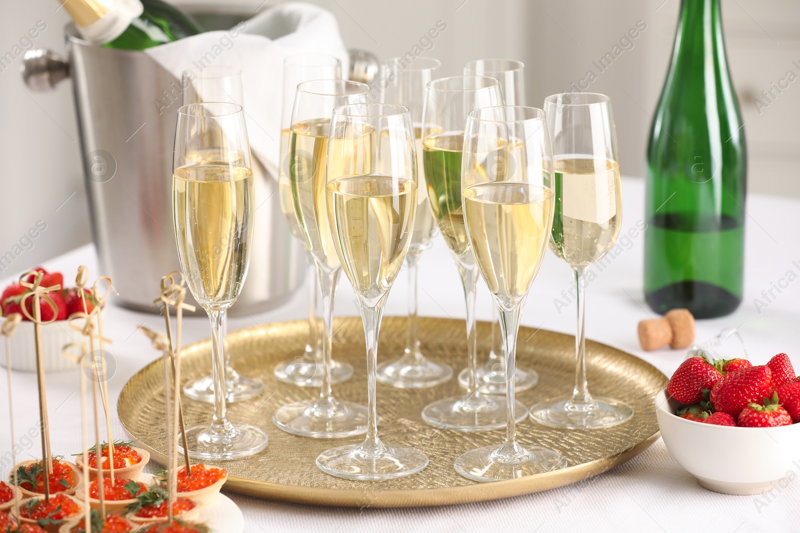 Photo of Champagne, strawberries and canapes with red caviar on white table