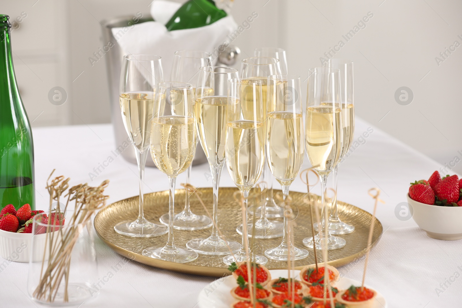 Photo of Champagne, strawberries and canapes with red caviar on white table