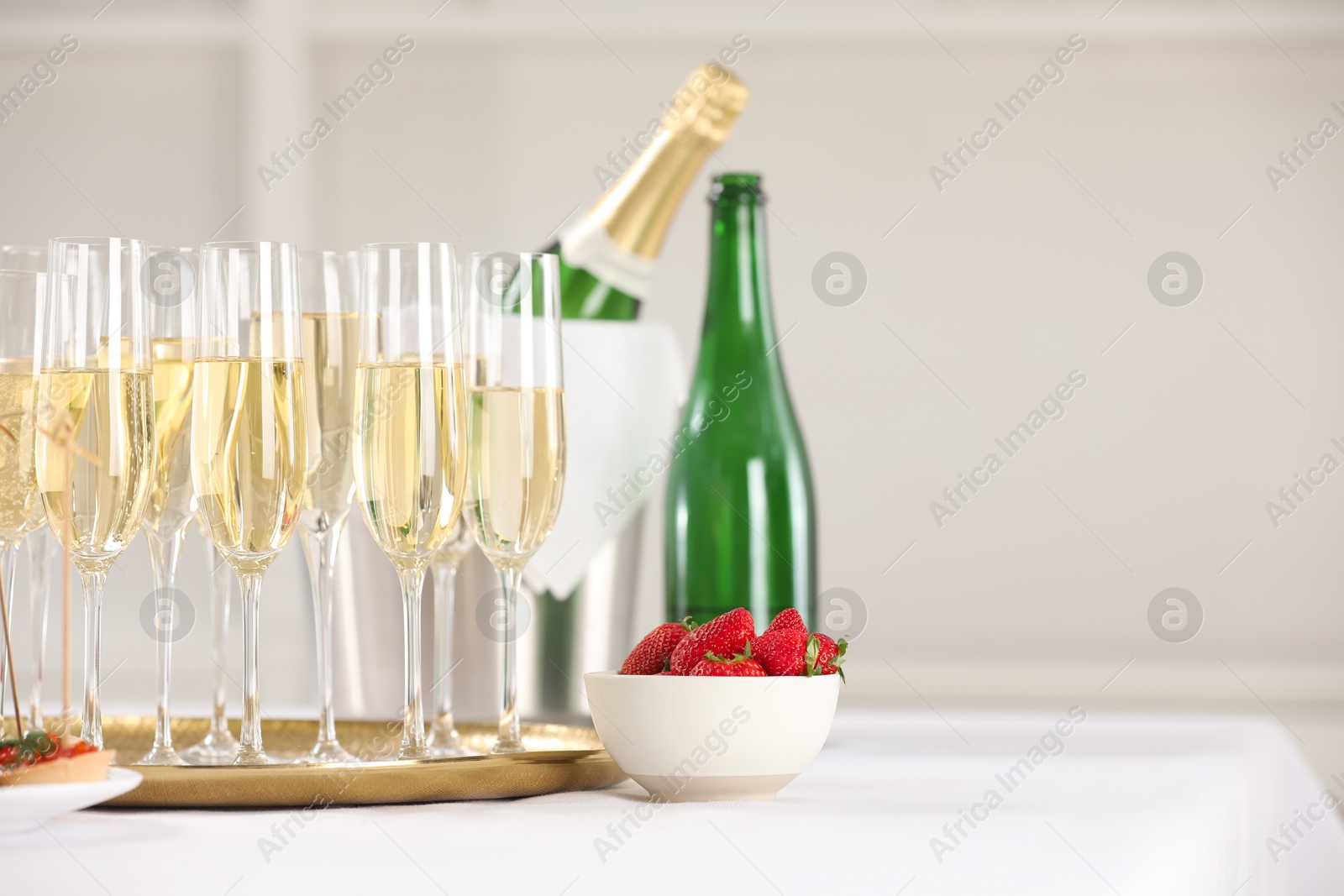 Photo of Champagne and strawberries on white table. Space for text