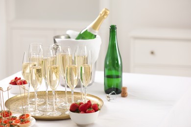 Photo of Champagne, strawberries and canapes with red caviar on white table. Space for text