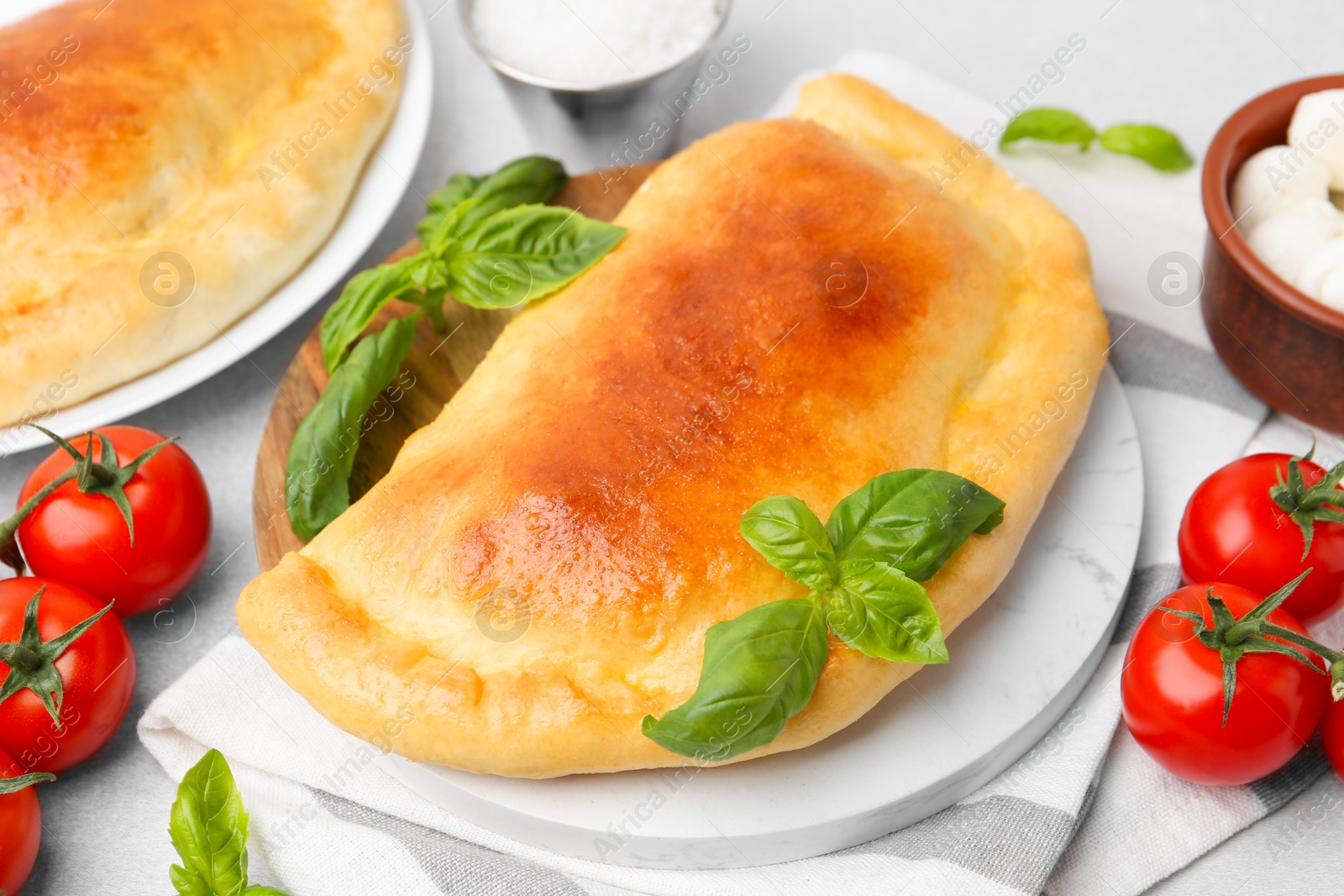 Photo of Tasty vegetarian calzones with basil, tomatoes and mozzarella cheese on table, closeup