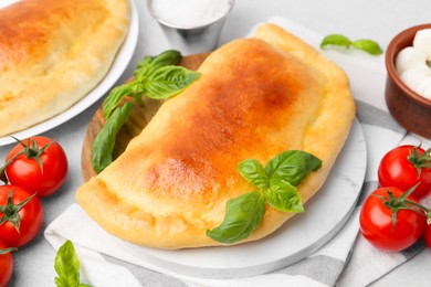 Photo of Tasty vegetarian calzones with basil, tomatoes and mozzarella cheese on table, closeup